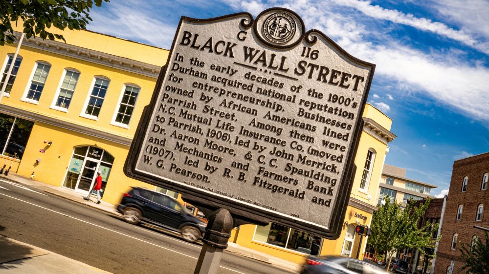 A sign stands on Parrish Street with information about Black Wall Street in Durham.