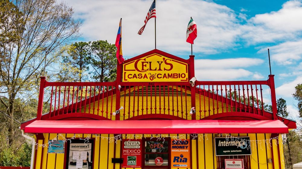 The yellow and red Cely's Casa De Cambio sits as the front of Tacos Nacos.