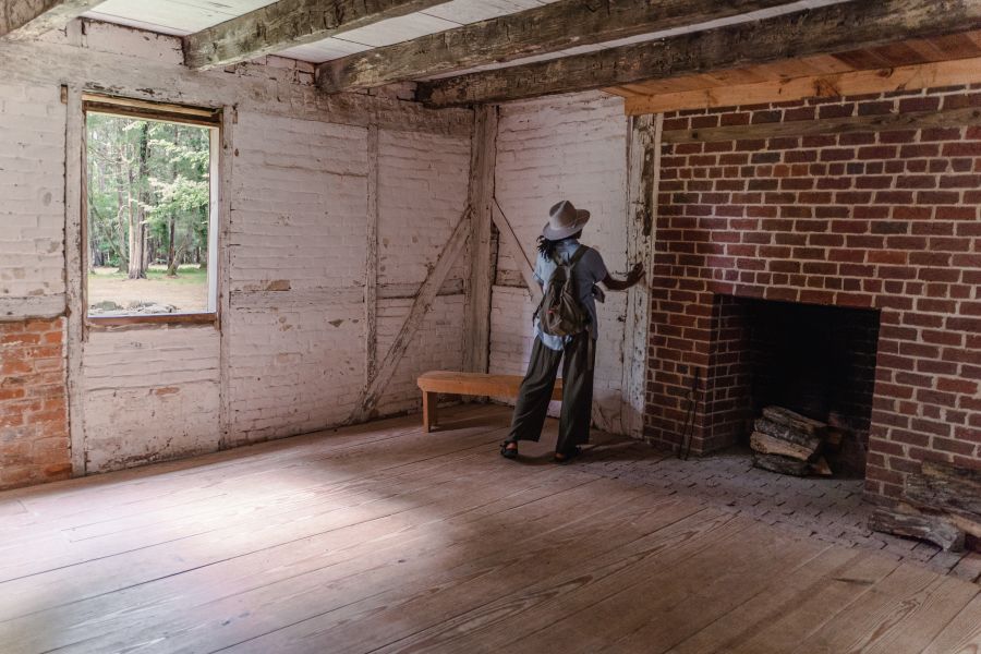 A visitor to Historic Stagville stands inside the dwelling at Horton Grove.